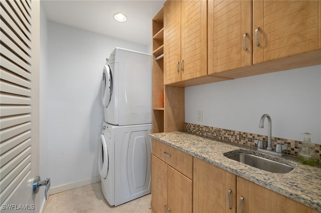 laundry room featuring cabinets, stacked washer / dryer, and sink