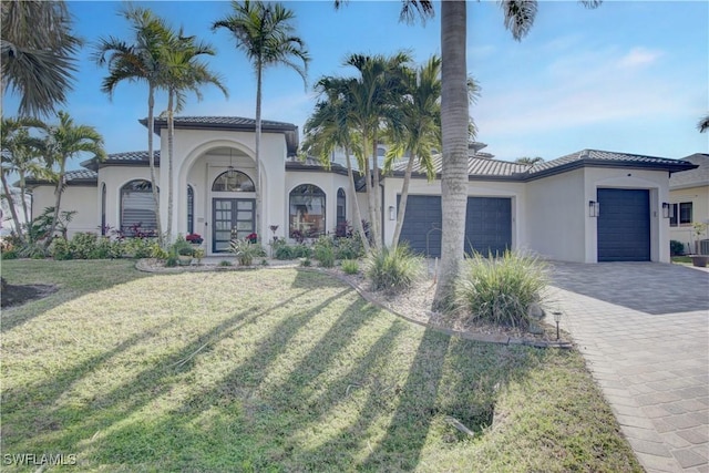 mediterranean / spanish-style house featuring a garage, a front lawn, and french doors