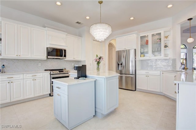 kitchen featuring arched walkways, visible vents, a kitchen island, stainless steel appliances, and a sink