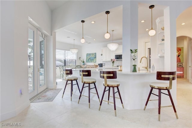 kitchen with a breakfast bar area, hanging light fixtures, light countertops, white cabinetry, and recessed lighting