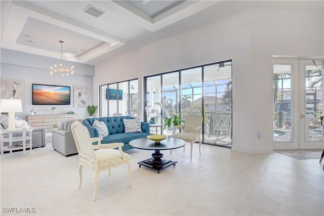 tiled living area with a tray ceiling, a healthy amount of sunlight, a notable chandelier, and a towering ceiling