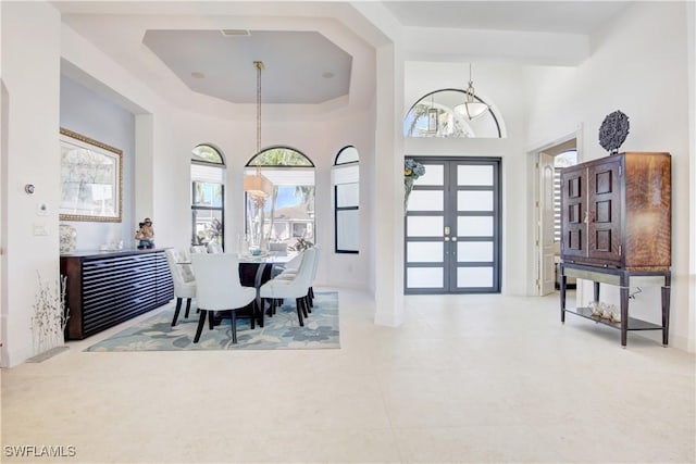 dining space with baseboards, a high ceiling, visible vents, and french doors