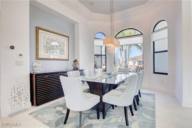 dining area featuring light tile patterned floors, a towering ceiling, and baseboards