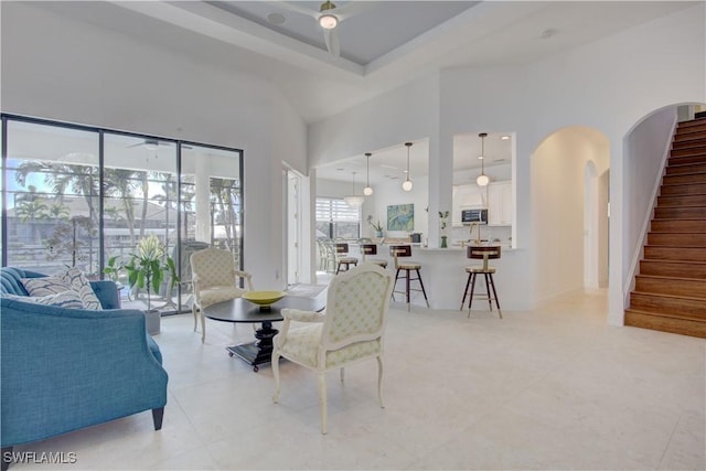 dining room featuring stairs, a high ceiling, light tile patterned floors, and arched walkways