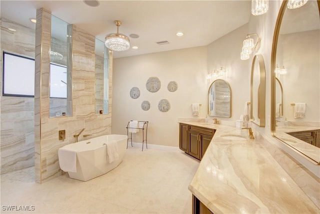 bathroom featuring recessed lighting, visible vents, vanity, a freestanding tub, and baseboards