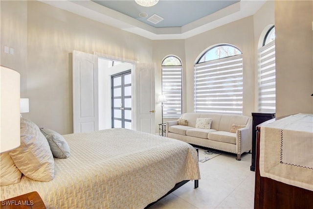 bedroom with light tile patterned floors, a tray ceiling, and visible vents