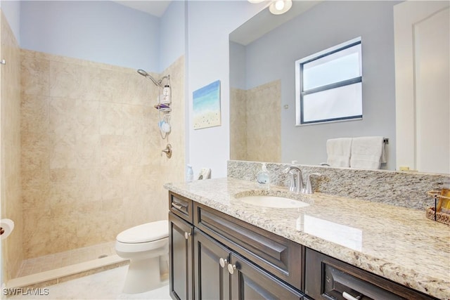 bathroom featuring toilet, a tile shower, and vanity