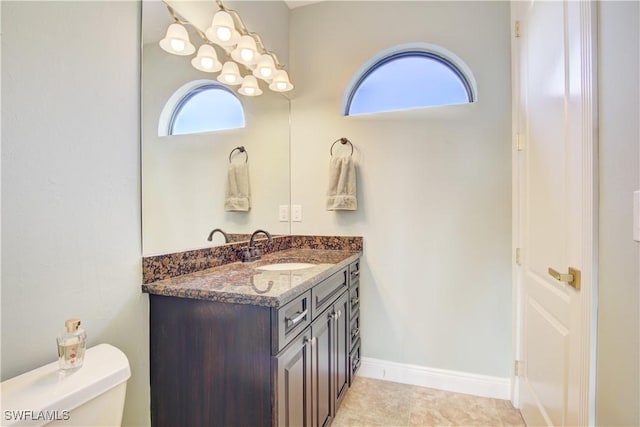 bathroom featuring a wealth of natural light, vanity, toilet, and baseboards