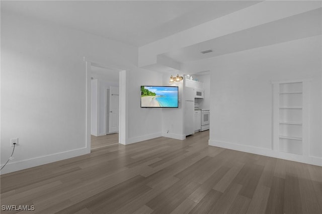 unfurnished living room with built in shelves, visible vents, baseboards, and wood finished floors