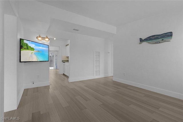 unfurnished living room with visible vents, light wood-style flooring, and baseboards