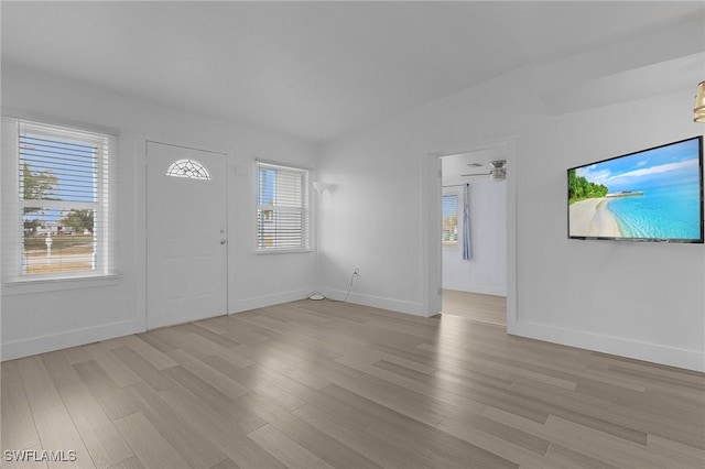 foyer with lofted ceiling, light wood finished floors, and baseboards