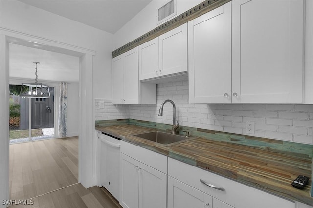 kitchen featuring butcher block countertops, white cabinets, white dishwasher, and a sink