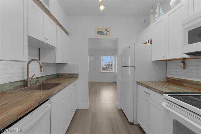 kitchen with butcher block counters, white appliances, a sink, and white cabinets