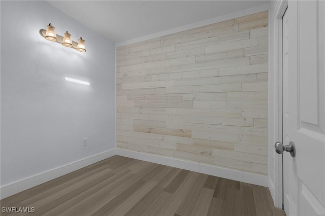 empty room with wood walls, baseboards, and dark wood-type flooring