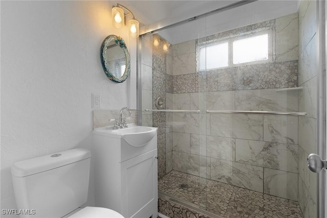 full bathroom with a stall shower, a textured wall, vanity, and toilet