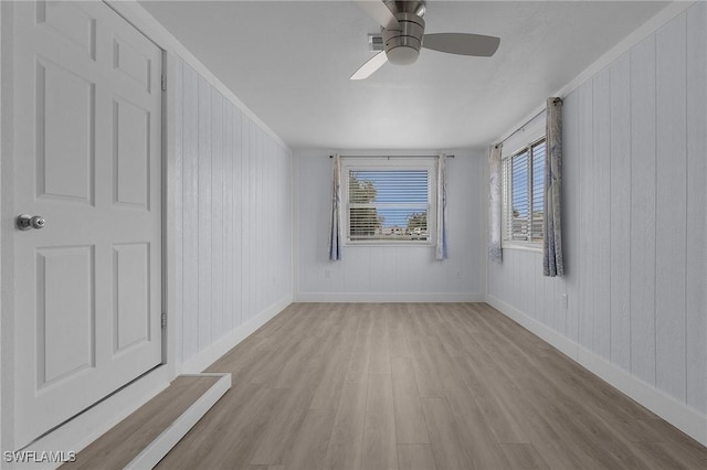 empty room featuring light wood-type flooring, ceiling fan, and baseboards