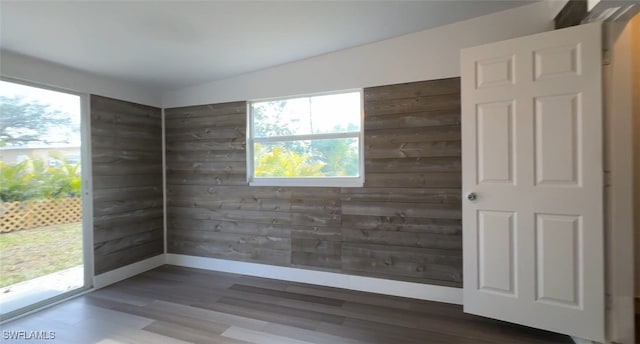 spare room featuring wooden walls, baseboards, and wood finished floors