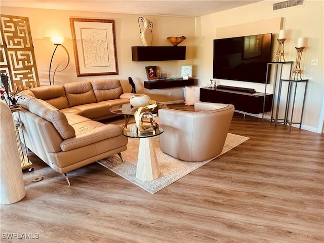 living area with baseboards, visible vents, and wood finished floors