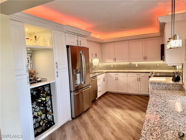 kitchen with stainless steel appliances, backsplash, light wood-style flooring, and light stone countertops