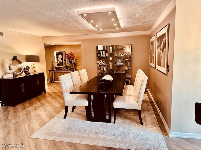 dining room with a textured ceiling, recessed lighting, wood finished floors, and baseboards