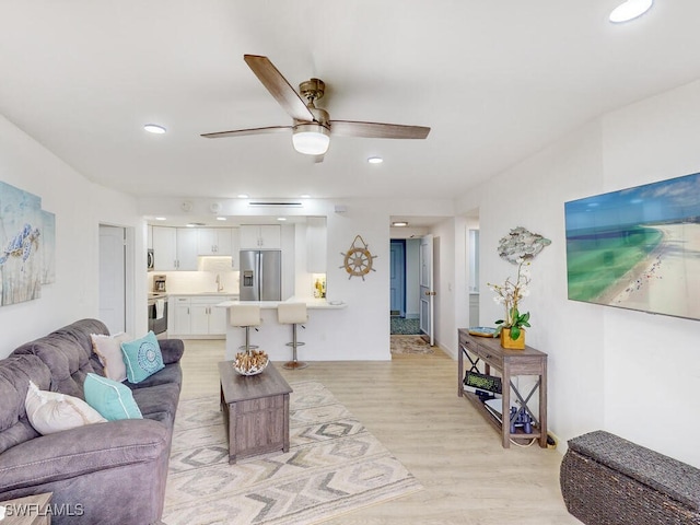 living room with light hardwood / wood-style floors, sink, and ceiling fan