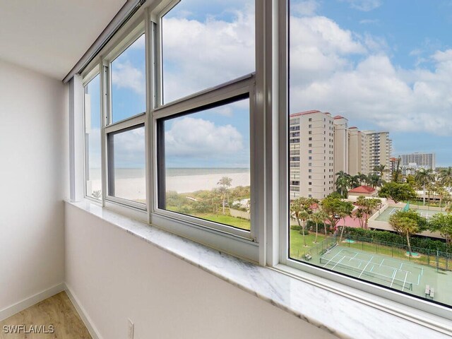 room details with hardwood / wood-style flooring, a water view, and a beach view