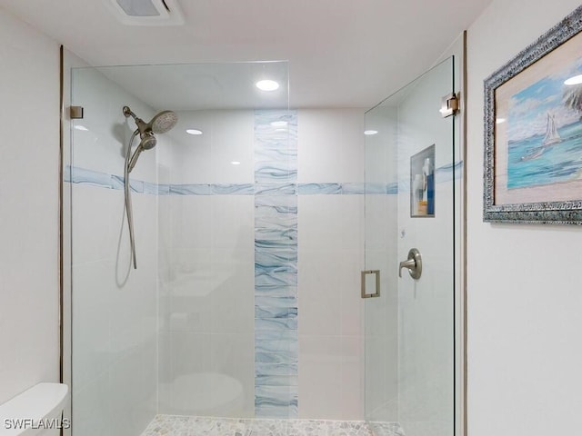 bathroom featuring a shower with shower door and toilet