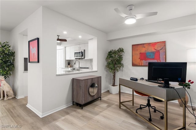 office area featuring ceiling fan, sink, and light hardwood / wood-style flooring