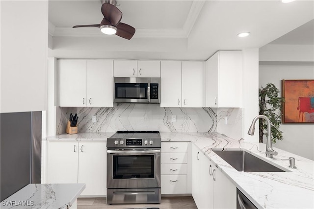 kitchen with white cabinets, stainless steel appliances, decorative backsplash, sink, and light stone counters