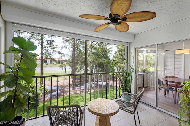 sunroom / solarium featuring ceiling fan and a water view