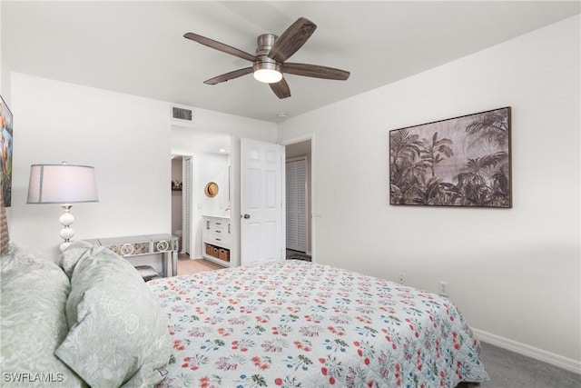 bedroom with ceiling fan, light colored carpet, and connected bathroom