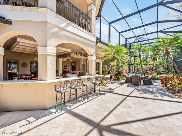 view of patio with a bar, a balcony, and glass enclosure