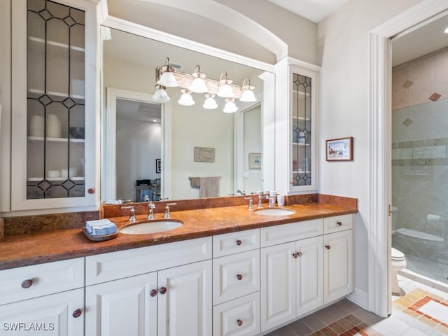 bathroom featuring tile patterned floors, vanity, toilet, and a tile shower