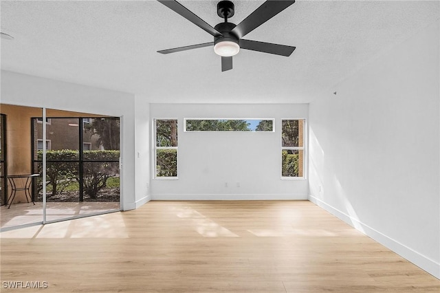 empty room with ceiling fan, a textured ceiling, plenty of natural light, and wood finished floors
