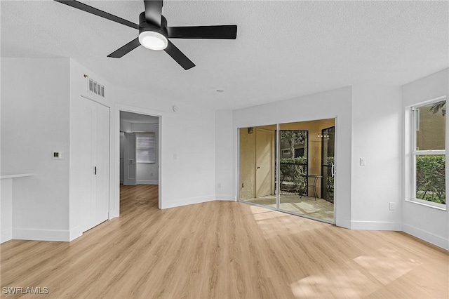 unfurnished room with a textured ceiling, a ceiling fan, light wood-style flooring, and baseboards