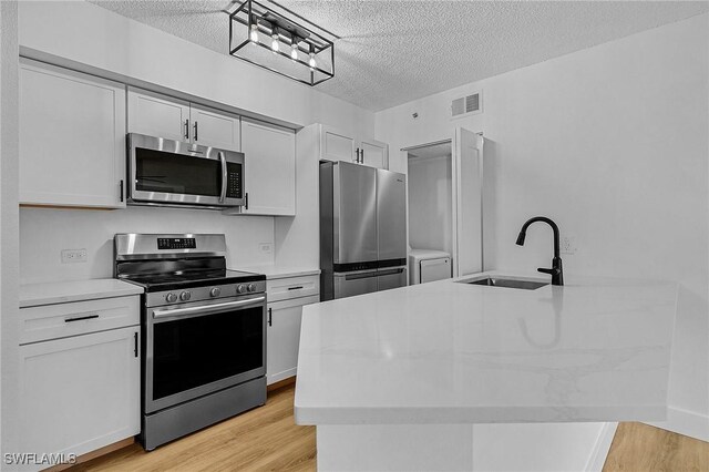 kitchen featuring stainless steel appliances, sink, a textured ceiling, and white cabinets