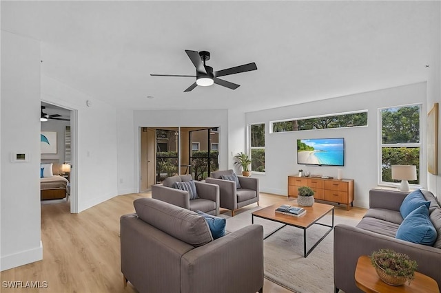 living room featuring baseboards, light wood-style floors, and ceiling fan