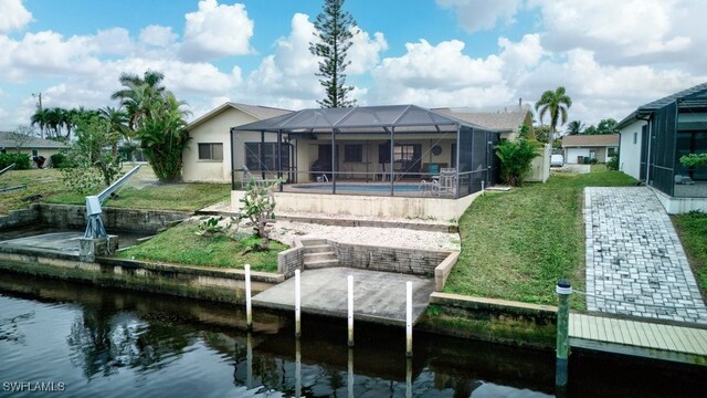 rear view of house with a lanai, a water view, and a yard