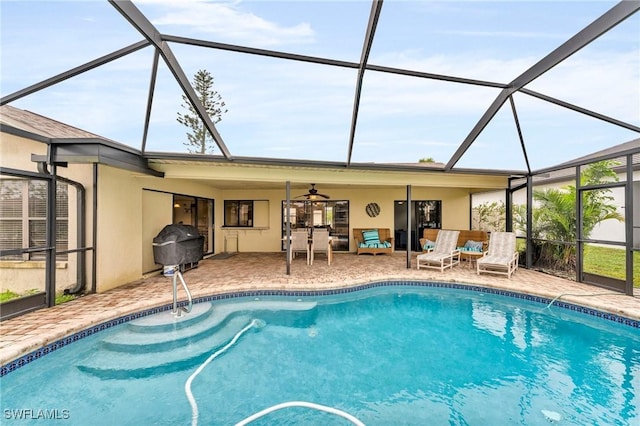 view of swimming pool with ceiling fan, a patio area, and glass enclosure