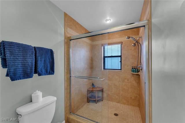 bathroom featuring toilet and a shower with door