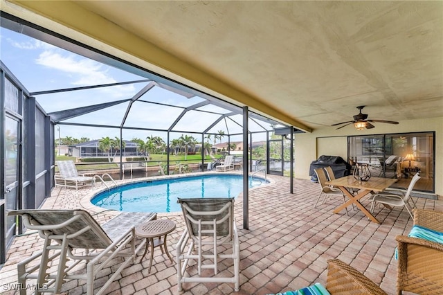 view of swimming pool featuring a patio area, glass enclosure, and grilling area