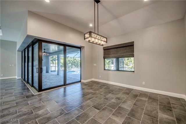 empty room with vaulted ceiling, ceiling fan, and a wealth of natural light