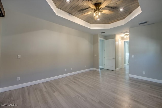 unfurnished room featuring wooden ceiling, light hardwood / wood-style floors, a tray ceiling, and ceiling fan