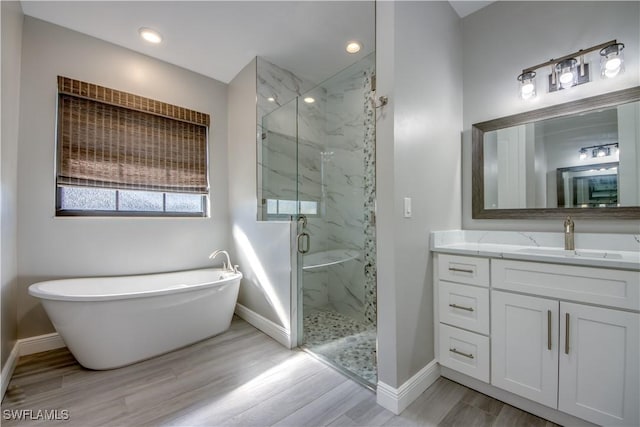 bathroom with independent shower and bath, hardwood / wood-style flooring, and vanity