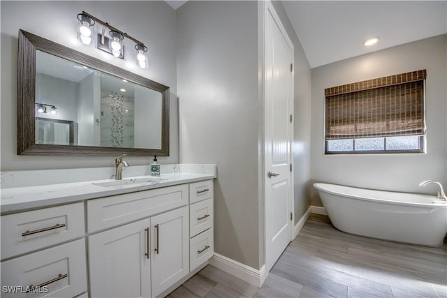 bathroom featuring walk in shower, baseboards, a freestanding tub, wood finished floors, and vanity