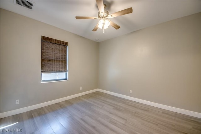 empty room with visible vents, baseboards, wood finished floors, and a ceiling fan