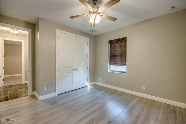 unfurnished bedroom with visible vents, wood finished floors, a closet, baseboards, and ceiling fan