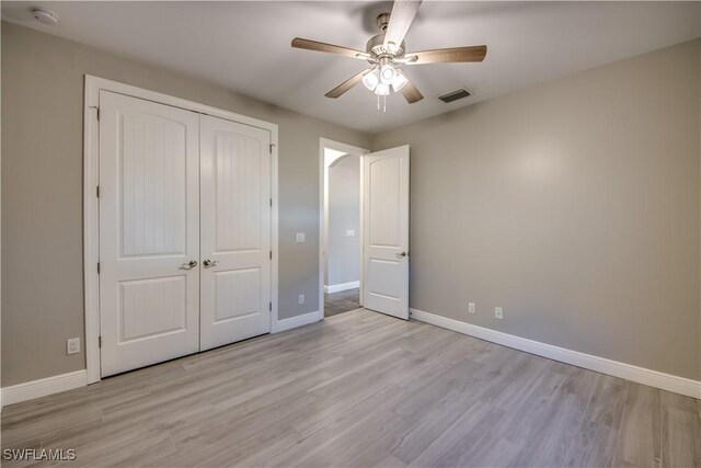 unfurnished bedroom with ceiling fan, light hardwood / wood-style floors, and a closet