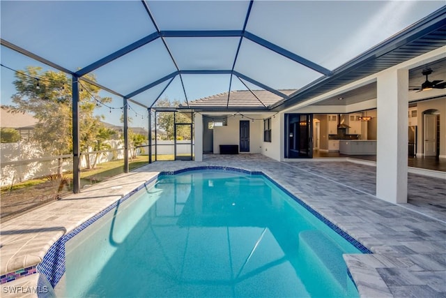 view of pool with ceiling fan, glass enclosure, and a patio area