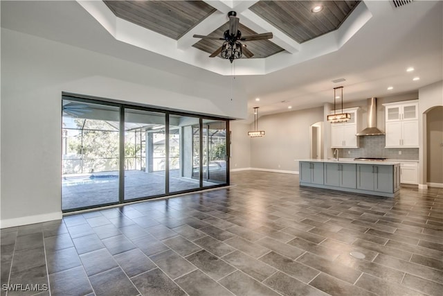 unfurnished living room with beamed ceiling, coffered ceiling, recessed lighting, baseboards, and ceiling fan